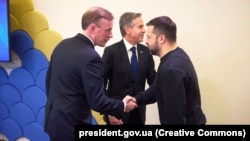 Jake Sullivan amerikai nemzetbiztonsági tanácsadó kezet ráz Volodimir Zelenszkij ukrán elnökkel Davosban. Középen Antony Blinken külügyminiszter látható 2024. január 16-án