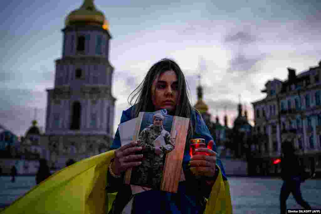 O femeie ține o lumânare și fotografia soțului ei, care a fost capturat la Mariupol, în timpul unei ceremonii care a marcat Ziua Voluntarilor, la Kiev, pe 14 martie.
