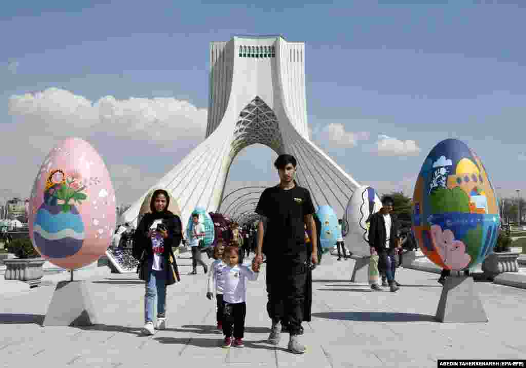 O familie se plimbă printre decorațiuni colorate în formă de ouă, un simbol al Nouruz, sau al Anului Nou persan, în Piața Libertății din Teheran.