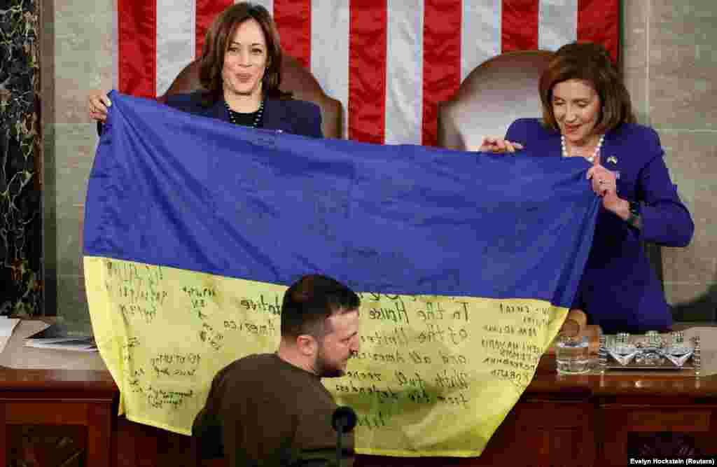 Харрис (слева) и спикер Палаты представителей США Нэнси Пелоси держат украинский флаг, привезенный президентом Украины Владимиром Зеленским из Бахмута во время его выступления на совместном заседании Конгресса США (21 декабря 2022 года). &laquo;Бахмут стоит, &ndash; сказал Зеленский под аплодисменты.&nbsp;&ndash; Украина держит свои позиции и никогда не сдастся&raquo;.