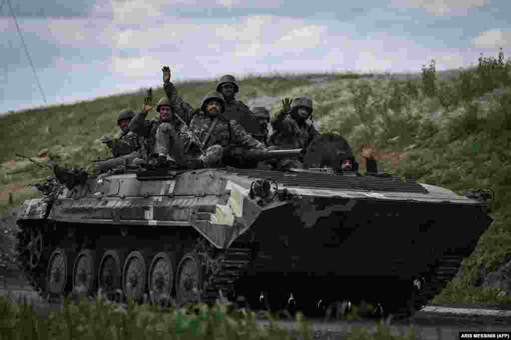 Ushtarët ukrainas përshëndesin me dorë teksa shkojnë drejt vijës së frontit pranë Lysychanskut.