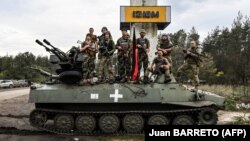Українські військові позують для фото на в'їзді до міста Ізюм Харківської області, яке було звільнене від російської армії раніше, 17 вересня 2022 року