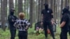 Люди в черном окружили женщину, пришедшую на акцию памяти в Сандармохе