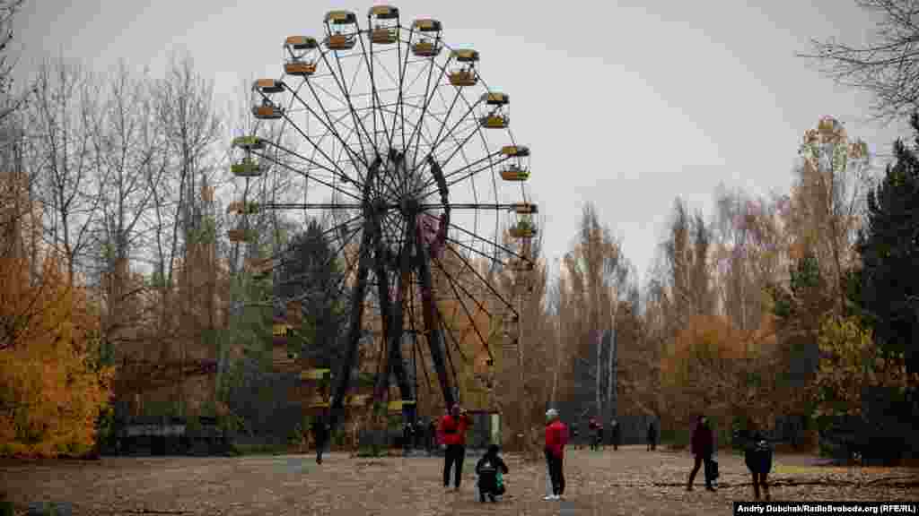 Сейчас Чернобыльская зона отчуждения превращается в один из самых популярных туристических мест в Украине. На фото – иностранные туристы у колеса обозрения «мертвого» города Припять