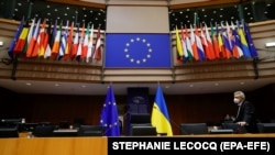 Az európai uniós és az ukrán zászló áll egymás mellett az asztaloknál, háttérben a tagországok zászlói az Európai Parlamentben, Brüsszelben 2022. március 1-jén - képünk illusztráció