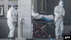 Медики у спеціальних костюмах транспортують інфікованого коронавірусом до лікарні, місто Ухань, 18 січня 2020 року