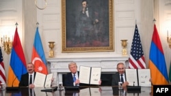 U.S. President Donald Trump (C), Azerbaijani President Ilham Aliyev (L) and Armenian Prime Minister Nikol Pashinian display the agreement they signed in the State Dining Room of the White House in Washington, DC on August 8, 2025.