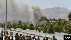 Afghan security personnel and bystanders look on as black smoke billows from the Afghan Parliament building in Kabul on June 22.