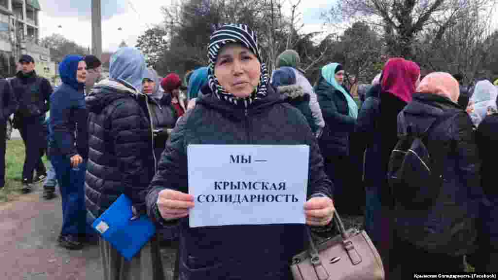 Діти і дружини кримськотатарських активістів тримають у руках аркуші паперу з написами «Ми – кримська солідарність» і «Поверніть 166-ти дітям їхніх батьків»