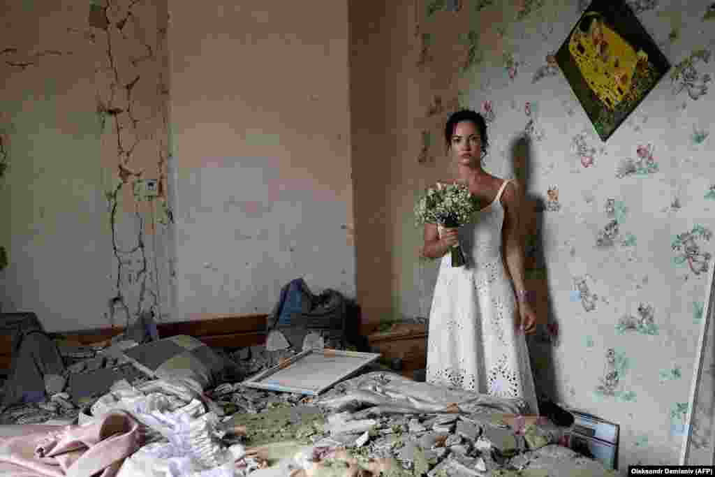 31-летняя Дария Стенюкова позирует для свадебной фотографии в своей разбомбленной квартире в Виннице, 16 июля. За день до свадьбы по городу, расположенному в 200 километрах к юго-западу от Киева, был нанесен ракетный удар. Дарья, инструктор по йоге, говорит, что она и ее жених не стали отказываться от свадьбы, несмотря на ракетную атаку, в результате которой погибли 26 человек. «Мой дом разрушен, но не наша жизнь», — сказала она AFP. «Это месседж всему миру — мы подчеркиваем, насколько сильны украинцы. Мы готовы жениться даже тогда, когда над нашими головами пролетают ракеты», — сказала она 