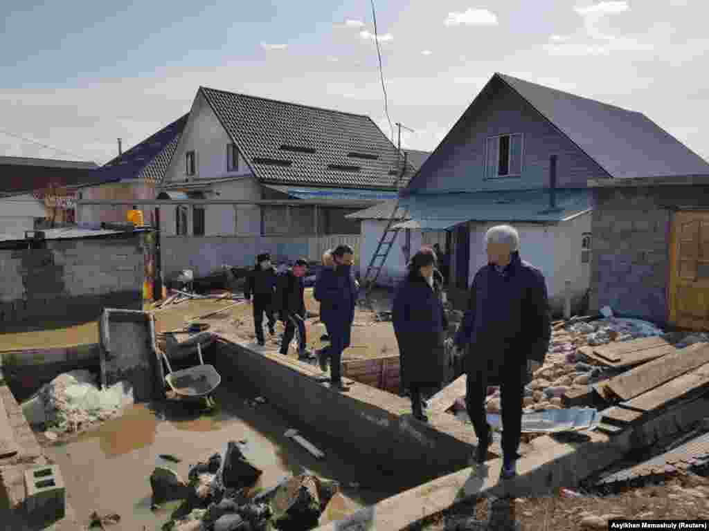 Шенеуніктер тасқыннан зардап шеккен үйден шығып келеді. 