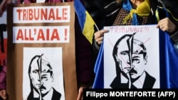 Жінки тримають плакати з написом «Міжнародний кримінальний суд у Гаазі» над портретами президента Росії Володимира Путіна та Олександра Лукашенка під час демонстрації на підтримку України. Рим, 24 лютого 2022 року