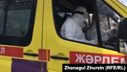Медицинский сотрудник в защитной одежде в автомобиле скорой помощи.