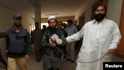 Pakistani Police escort a man through the halls of a court in Karachi.