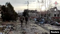 Російські військовослужбовці проходять повз зруйновану будівлю в Суджі. Курщина, Росія. 2024 рік