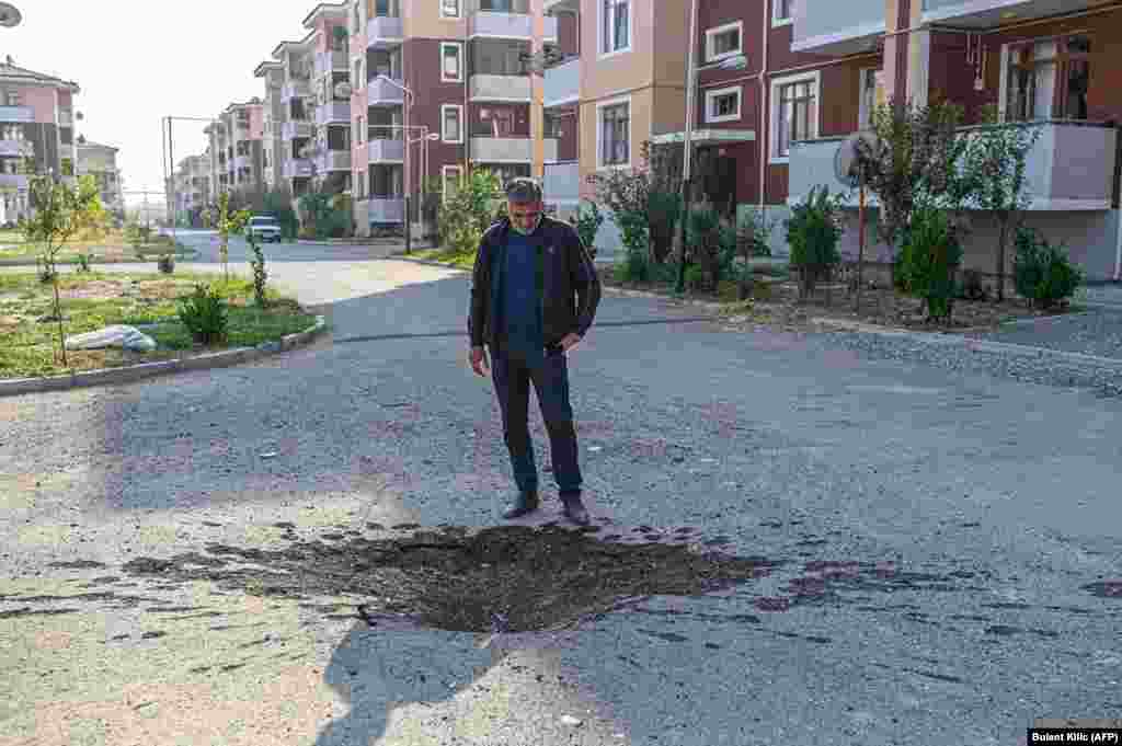 Еден човек гледа во кратер, на патот во Тертер, во близина на линијата на фронтот на конфликтот, на 18 октомври.